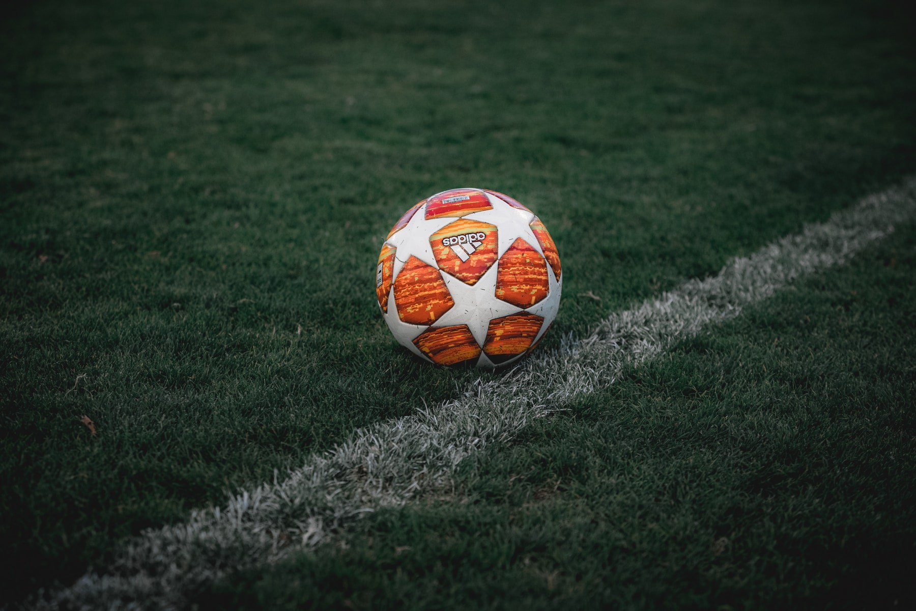 white and orange soccer ball on green grass field
